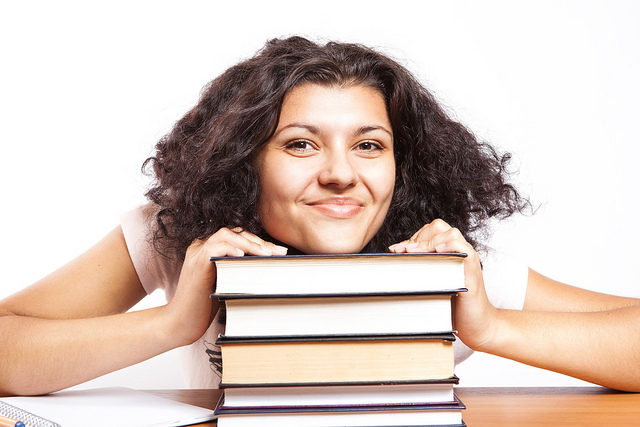 A university student with her head on her books giving a big smile by CollegeDegrees360 - http://bit.ly/2e2qYr1